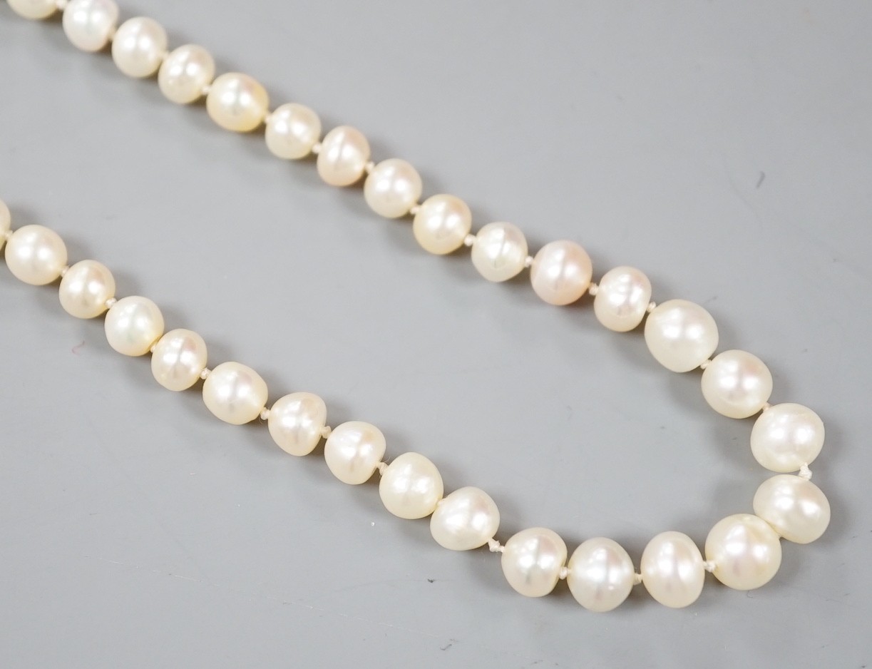 An early 20th century single strand possibly part natural? and part cultured pearl necklace, with diamond cluster set white metal clasp, 112cm.